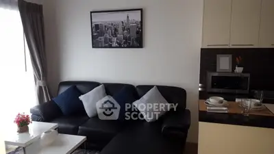 Modern living room with black leather sofa and stylish kitchen area