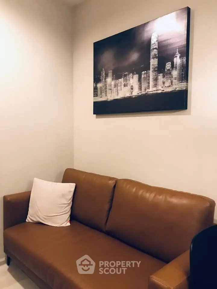 Cozy living room with brown leather sofa and cityscape artwork, perfect for modern urban living.
