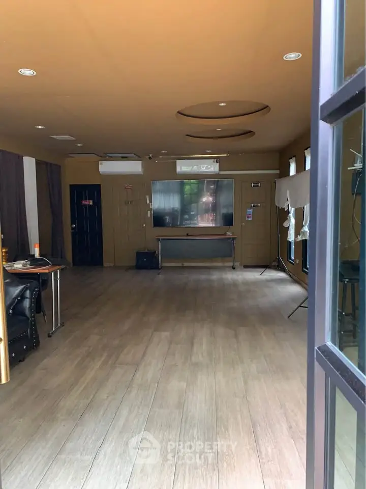 Spacious interior room with wooden flooring and modern lighting, ideal for versatile use.