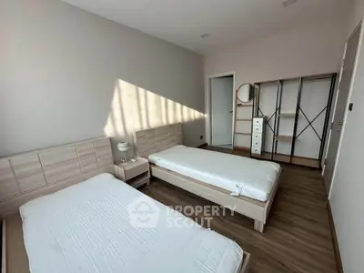 Spacious bedroom with twin beds and modern minimalist decor, perfect for comfortable living.