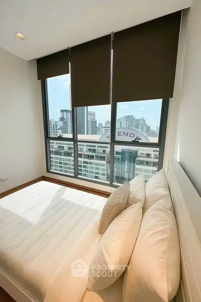 Bright bedroom with large windows offering stunning city views in modern apartment.