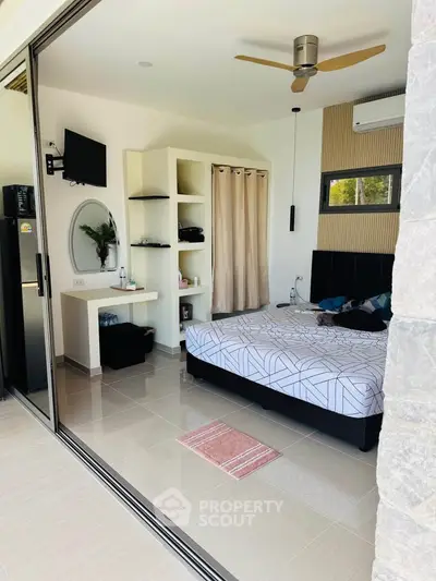 Modern bedroom with sliding glass doors, ceiling fan, and stylish decor for a cozy living experience.