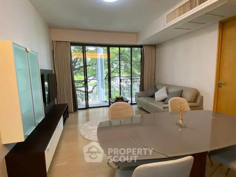 Spacious living room with modern furniture and large windows overlooking greenery.