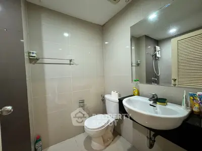 Modern bathroom with sleek fixtures and neutral tiles, featuring a large mirror and stylish sink.
