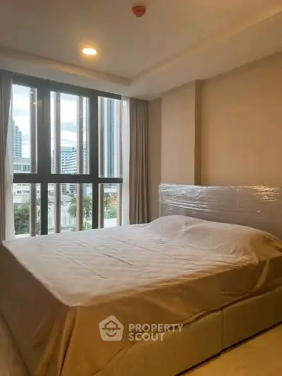 Spacious bedroom with large windows offering city views in modern apartment.