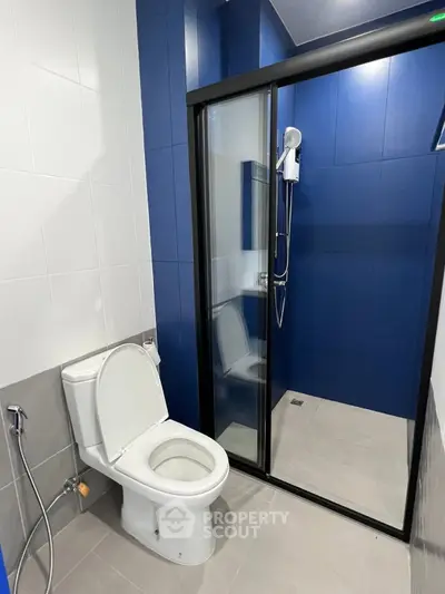 Modern bathroom with sleek blue tiles and glass shower enclosure