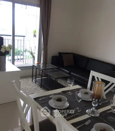 Modern living room with dining area and balcony view, featuring sleek furniture and elegant decor.