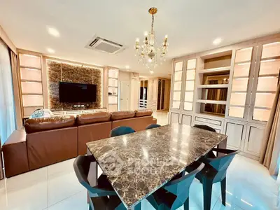 Luxurious living room with marble dining table, chandelier, and built-in shelves.
