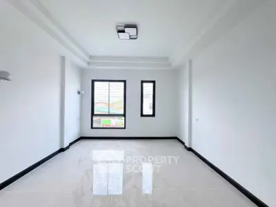 Spacious modern living room with large windows and sleek tile flooring.