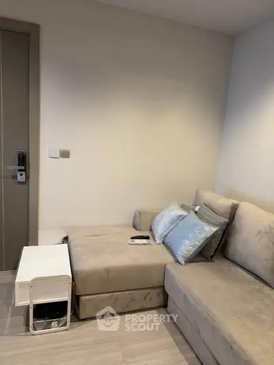 Cozy living room with modern beige sofa and sleek wooden flooring, perfect for relaxation.