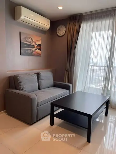 Modern living room with sleek furniture and large window offering natural light and city view.