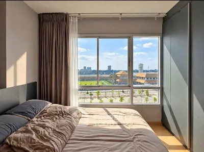 Spacious bedroom with large window offering stunning city view and natural light.