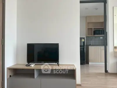 Modern apartment interior with sleek kitchen and cozy living area featuring a flat-screen TV.