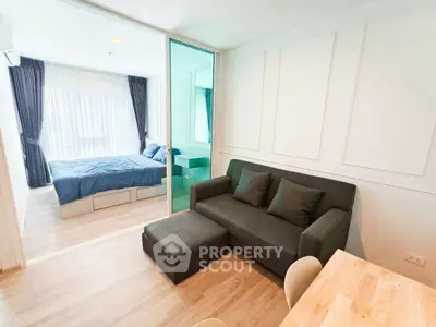 Modern apartment with cozy living room and bedroom separated by glass partition.