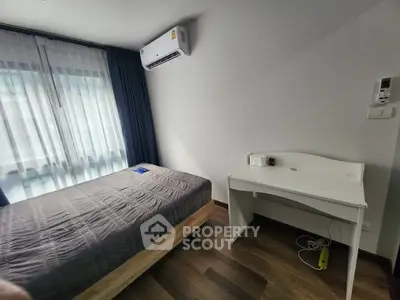 Modern bedroom with air conditioning and minimalist desk, featuring wooden flooring and natural light.