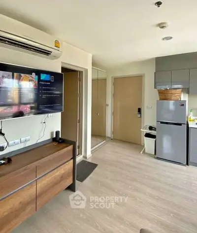 Modern apartment interior with sleek kitchen and cozy living area, featuring a wall-mounted TV and air conditioning.