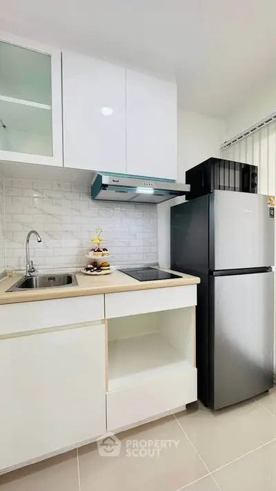 Modern kitchen with sleek cabinets, stainless steel fridge, and stylish backsplash in a compact layout.