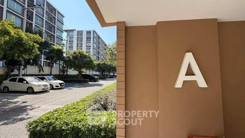 Modern apartment building exterior with parking and lush greenery