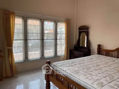 Spacious bedroom with elegant wooden furniture and large windows for natural light.