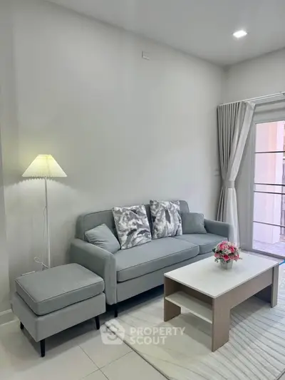 Modern living room with stylish sofa, elegant decor, and natural light from large windows.