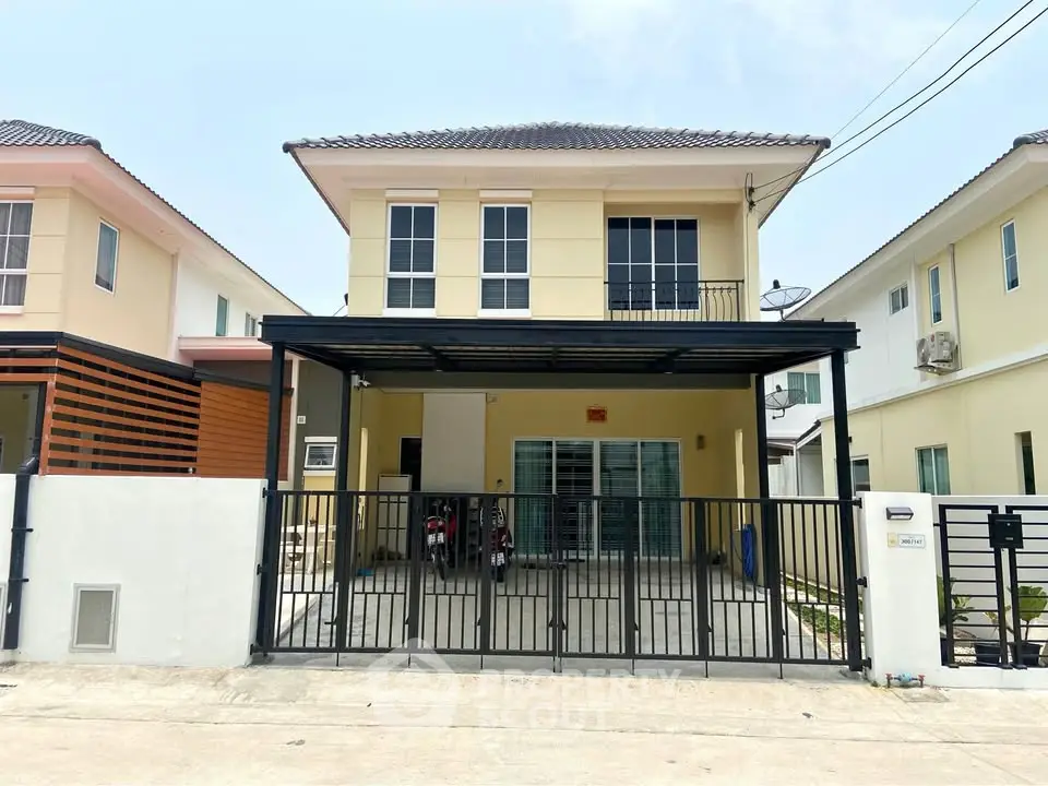 Charming two-story yellow house with gated driveway in a serene neighborhood.