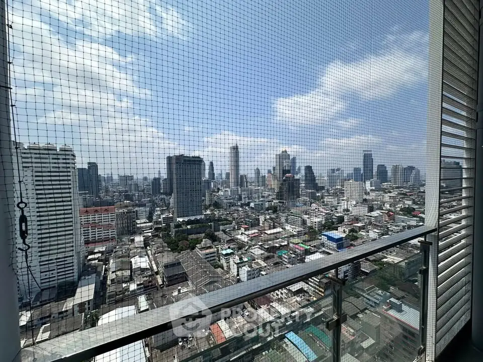 Stunning cityscape view from high-rise balcony with safety netting, showcasing urban skyline.