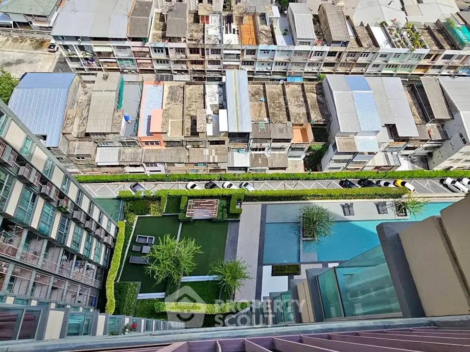 Stunning aerial view from high-rise building overlooking urban landscape and modern pool area.