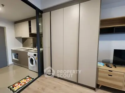 Modern kitchen with washing machine and sleek cabinetry in compact apartment.