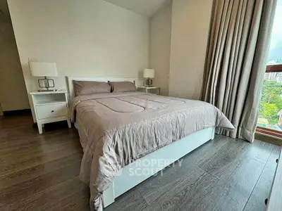Cozy bedroom with modern decor and large window offering natural light.