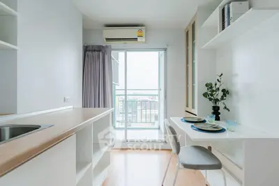 Modern kitchen with open layout and balcony view, featuring sleek countertops and dining area.