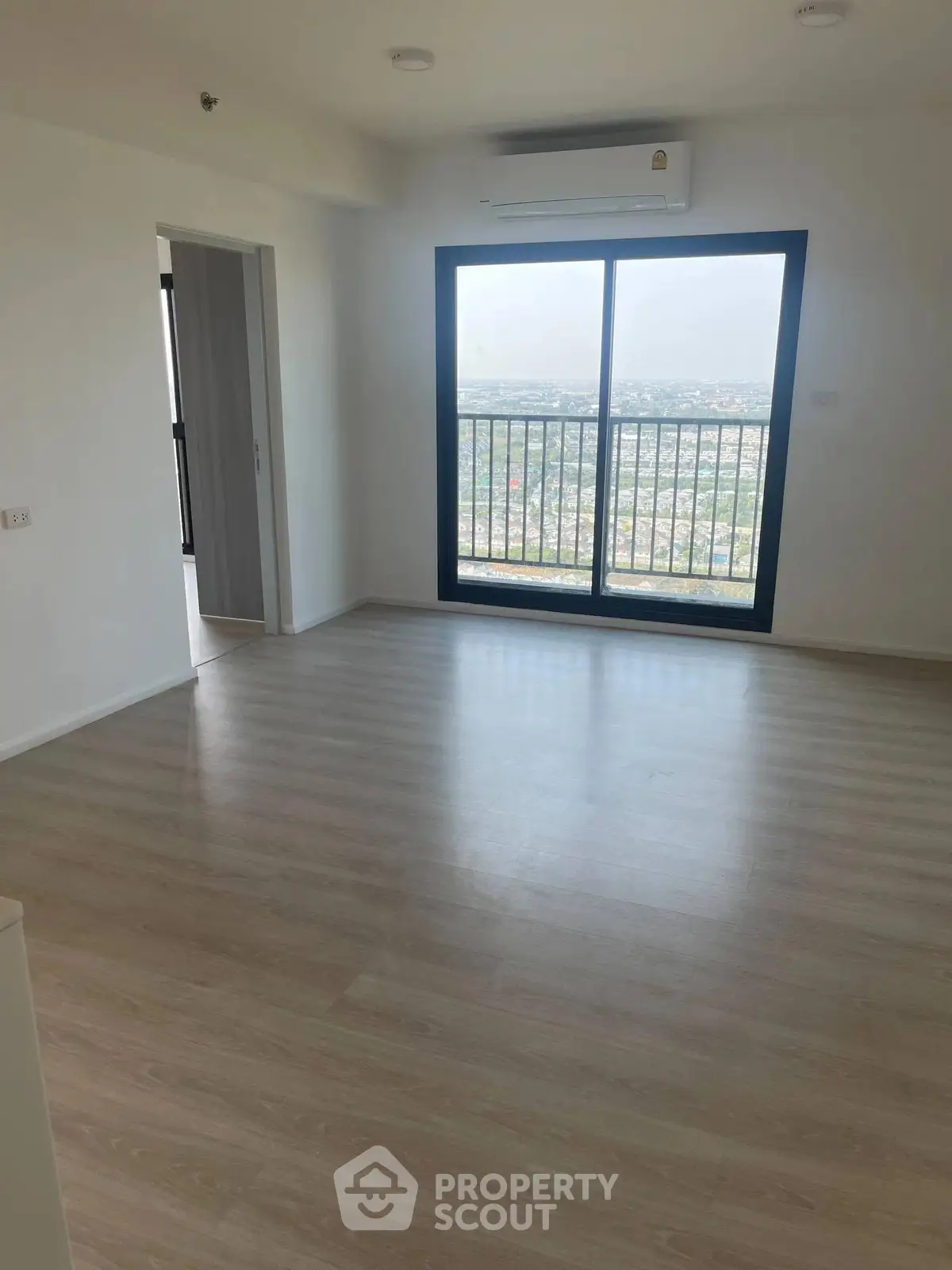 Spacious living room with large window offering stunning city views, perfect for modern living.