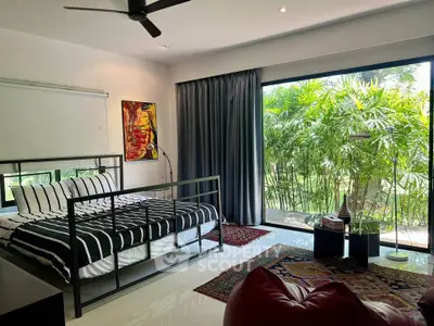 Spacious bedroom with modern decor and large window overlooking lush greenery.