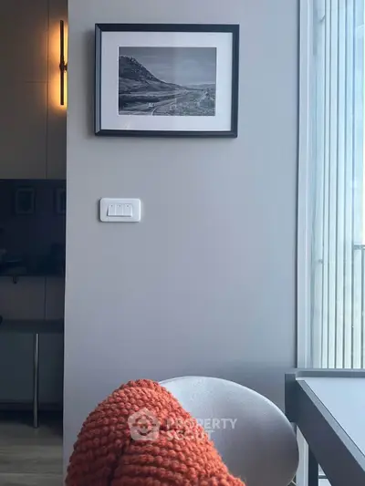 Modern interior with cozy chair, wall art, and natural light from large window.