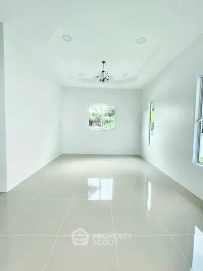 Spacious empty room with glossy tiled floor and elegant ceiling light fixture.