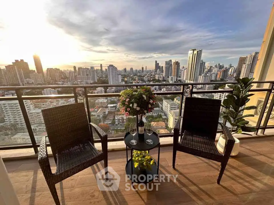 Stunning cityscape view from a high-rise balcony with elegant seating and lush greenery.