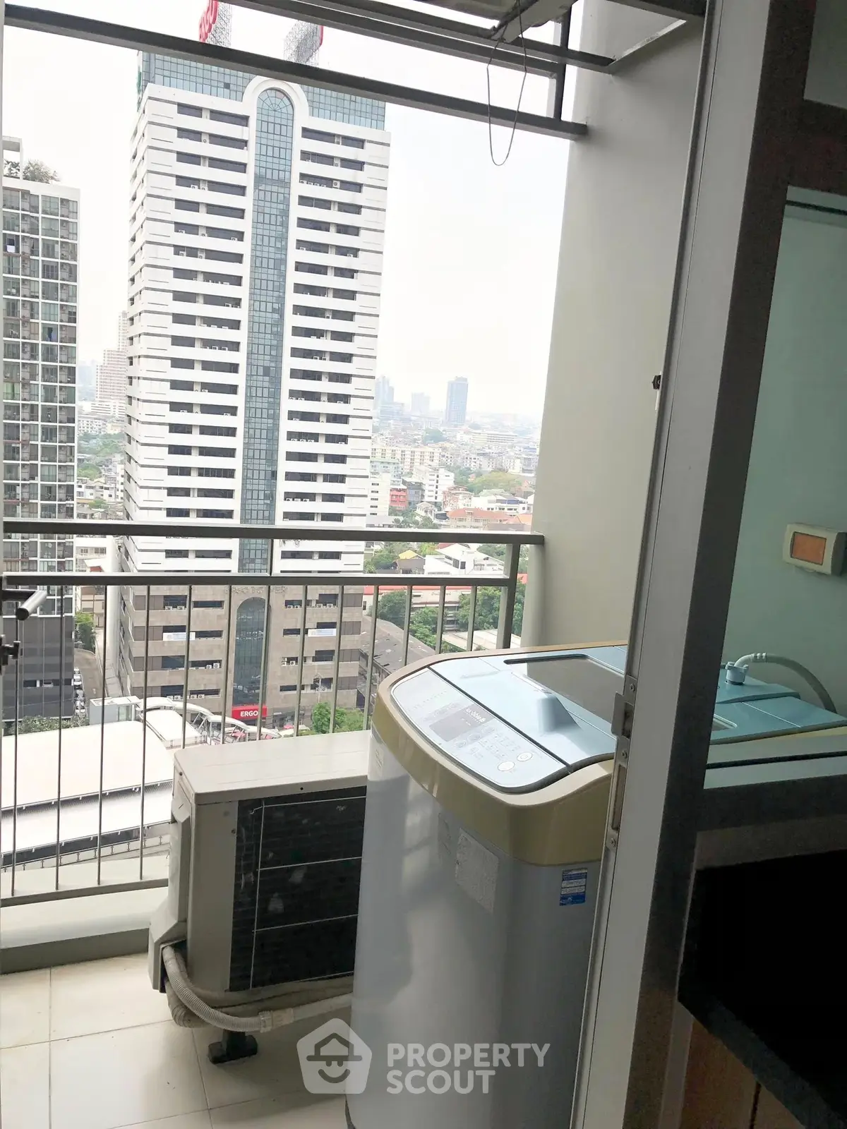 High-rise balcony with city view and washing machine setup.