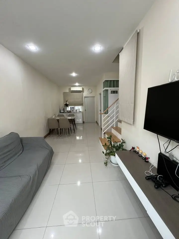 Modern living room with sleek design and open layout, featuring a cozy sofa and wall-mounted TV.