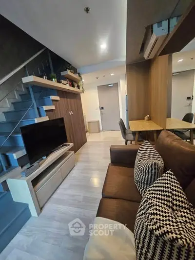 Modern living room with stylish decor and open staircase in a contemporary apartment.