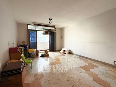 Spacious empty living room with tiled floor and balcony access, ready for customization.