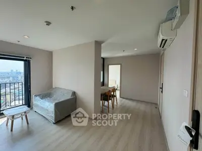 Modern living room with balcony view in a high-rise apartment, featuring sleek furniture and air conditioning.