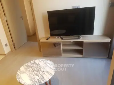 Modern living room with sleek TV stand and marble coffee table in cozy apartment.