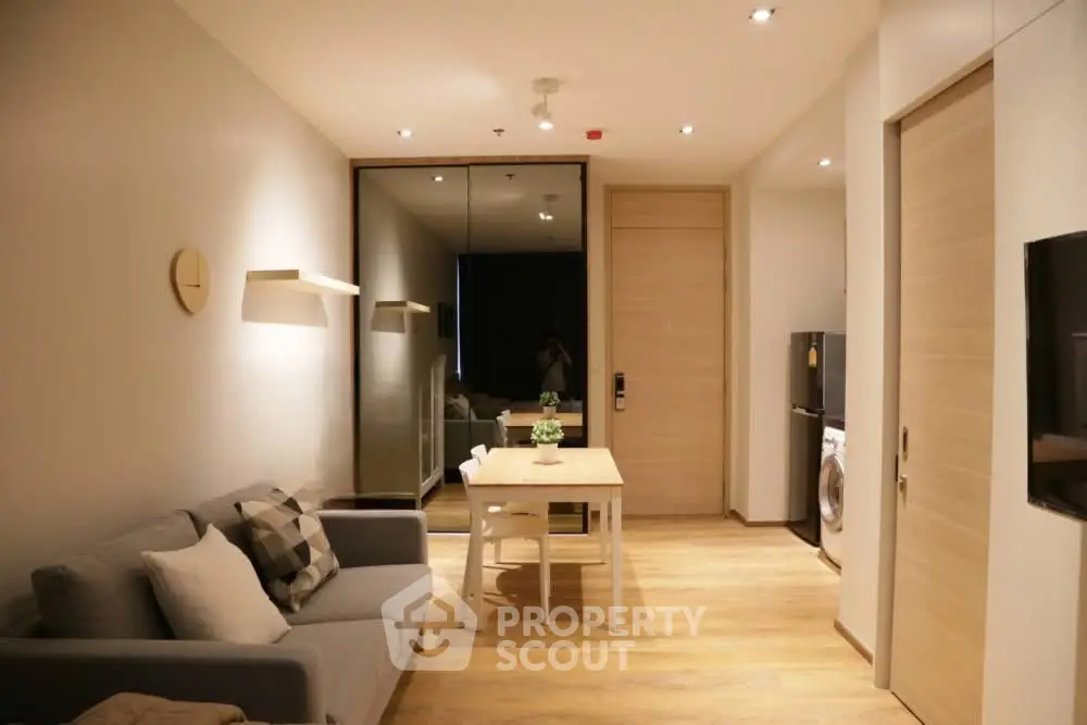 Modern living room with cozy sofa, dining table, and mirrored wall in stylish apartment.