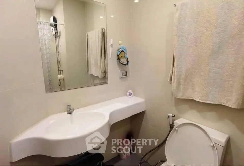 Modern bathroom with sleek white sink and wall-mounted mirror, featuring neutral tones and contemporary design.
