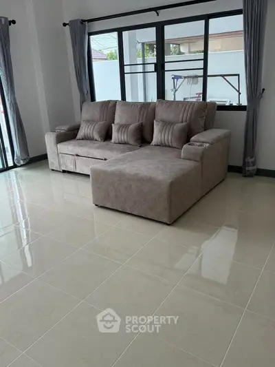 Spacious living room with modern gray sectional sofa and large windows for natural light.