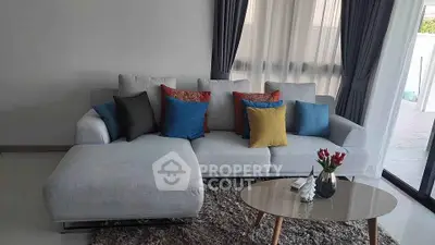 Modern living room with stylish sofa and colorful cushions, featuring a chic coffee table and elegant curtains.