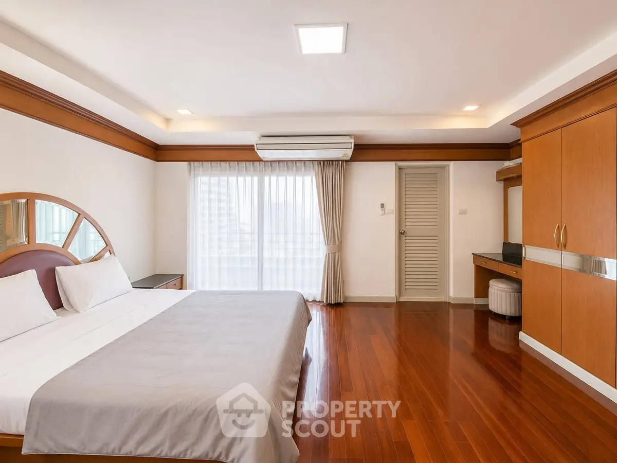 Spacious bedroom with wooden flooring and modern furnishings in a luxury apartment.