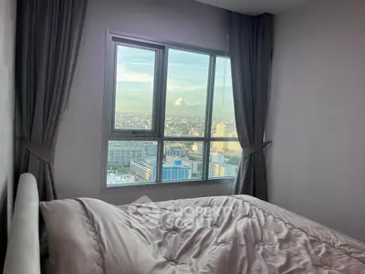 Cozy bedroom with large window offering stunning city views, perfect for urban living.