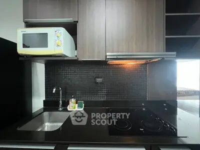 Modern kitchen with sleek black countertops, electric stove, and microwave, featuring a stylish backsplash.