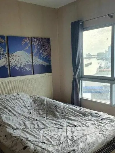 Cozy bedroom with large window and scenic artwork, offering natural light and a serene atmosphere.