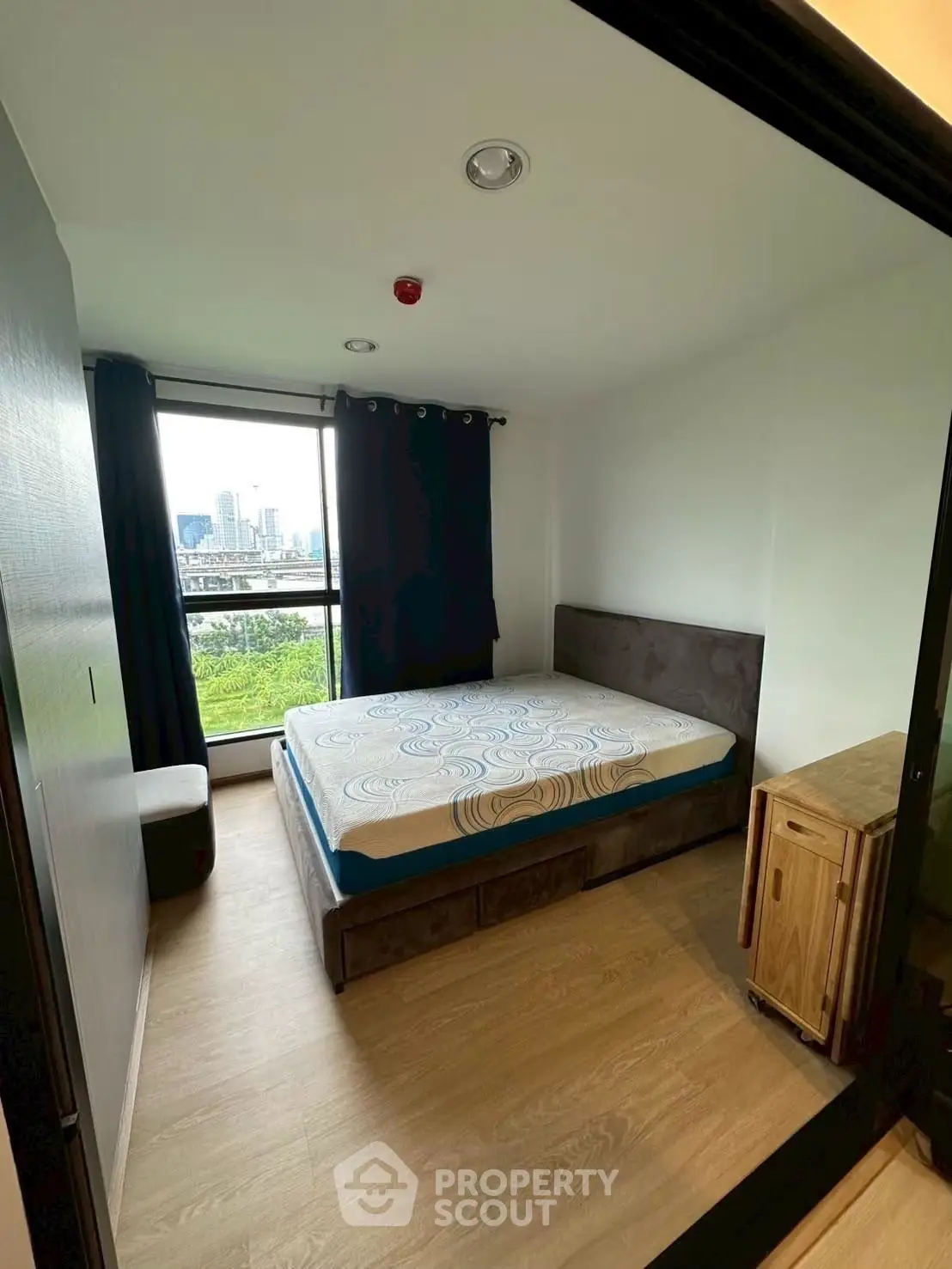 Cozy bedroom with city view, featuring a comfortable bed and modern decor, perfect for urban living.
